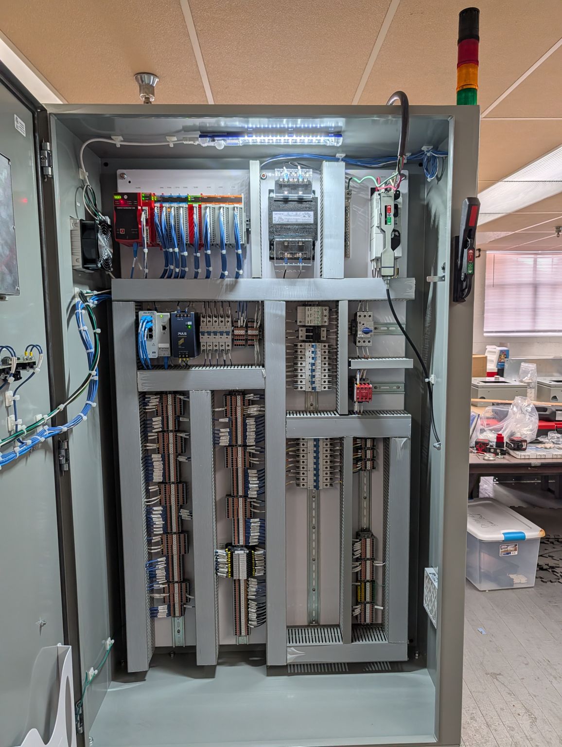 Inside of a control panel showing PLC modules, terminal blocks, and DIN rail wiring